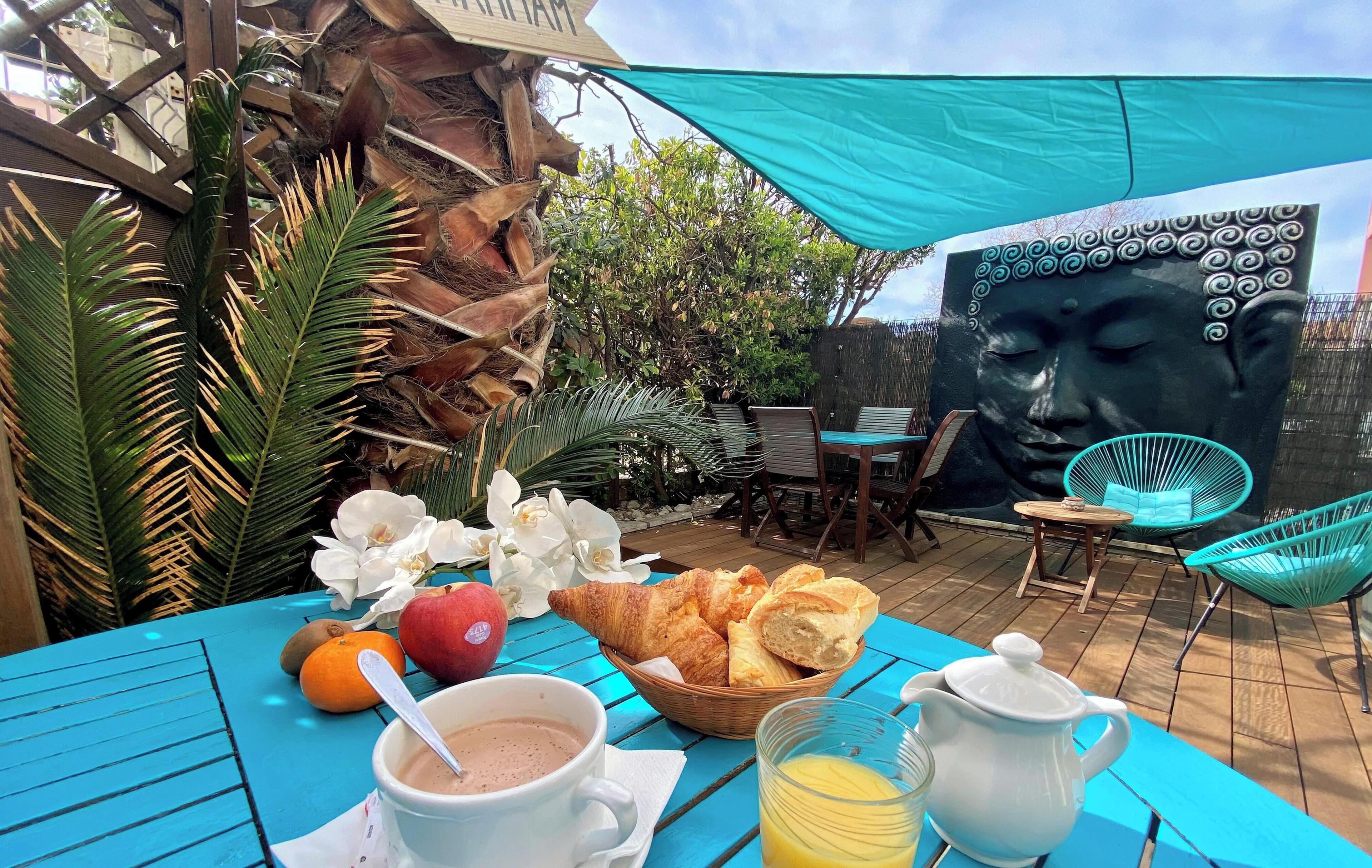 A table with breakfast items, a Buddha statue, and outdoor furniture.