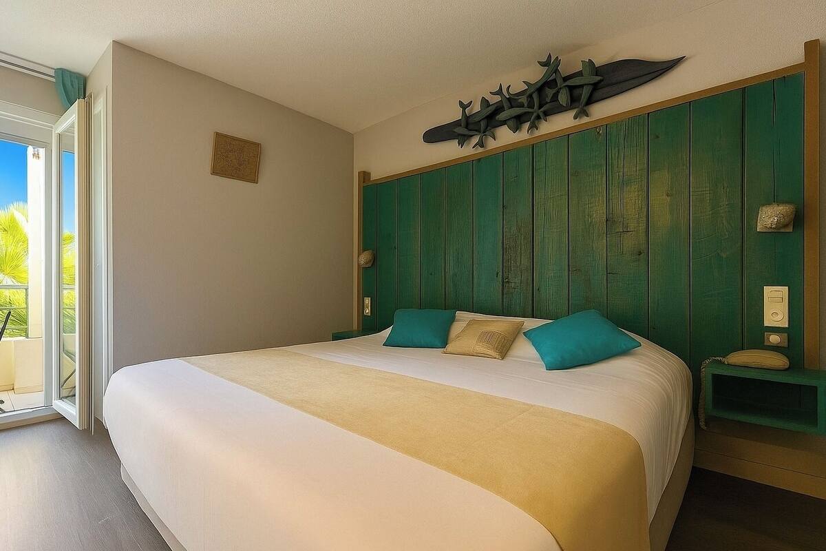 Une chambre d’hôtel avec un grand lit, une tête de lit verte, un balcon avec vue et un élément décoratif mural.