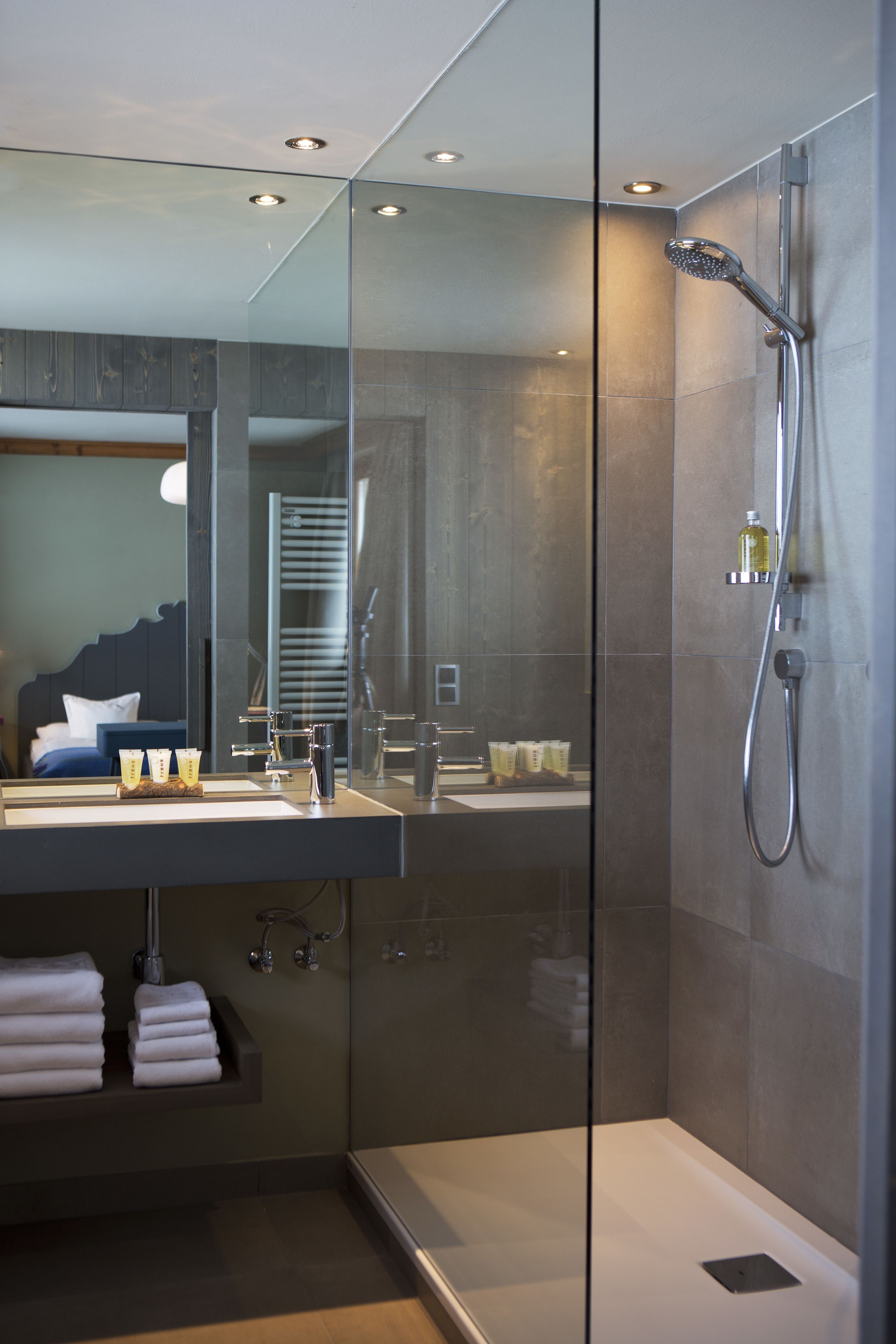 A modern bathroom with a glass-enclosed shower, a large mirror, and a vanity with a sink and towel rack.