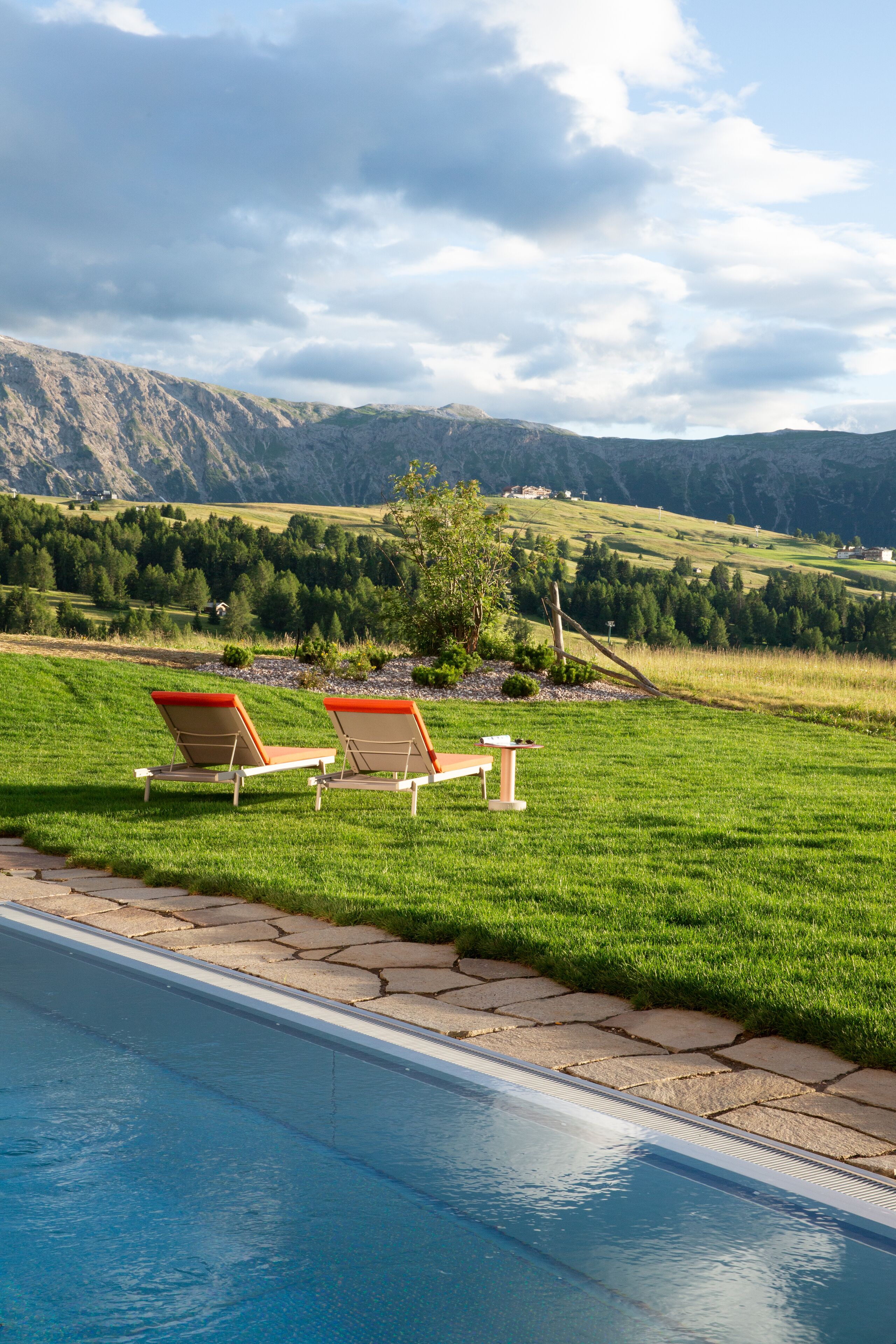 A poolside area with two lounge chairs and a stone pathway leading to the pool.