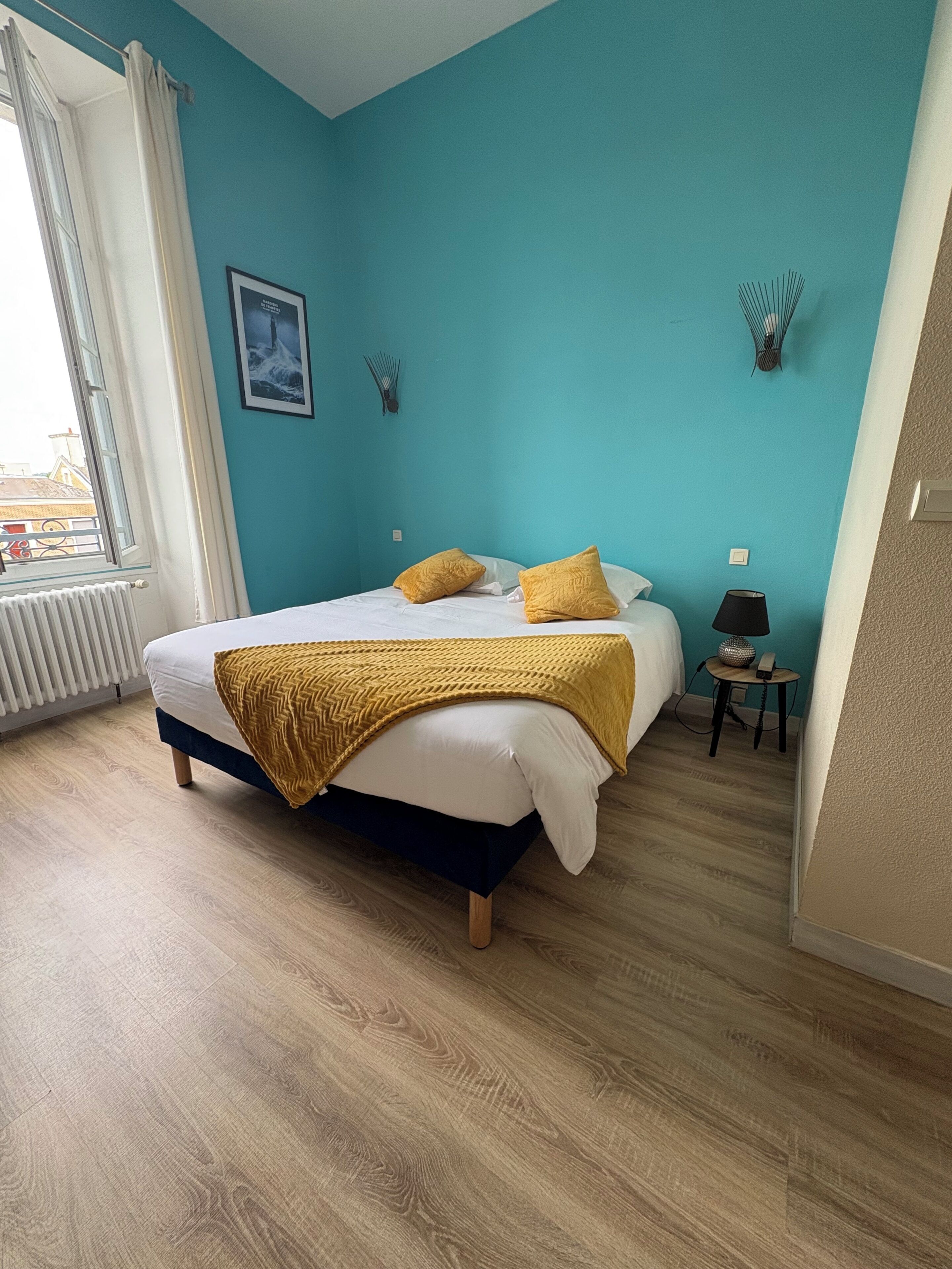 A bedroom with a bed, a window, a bedside table, and a lamp.