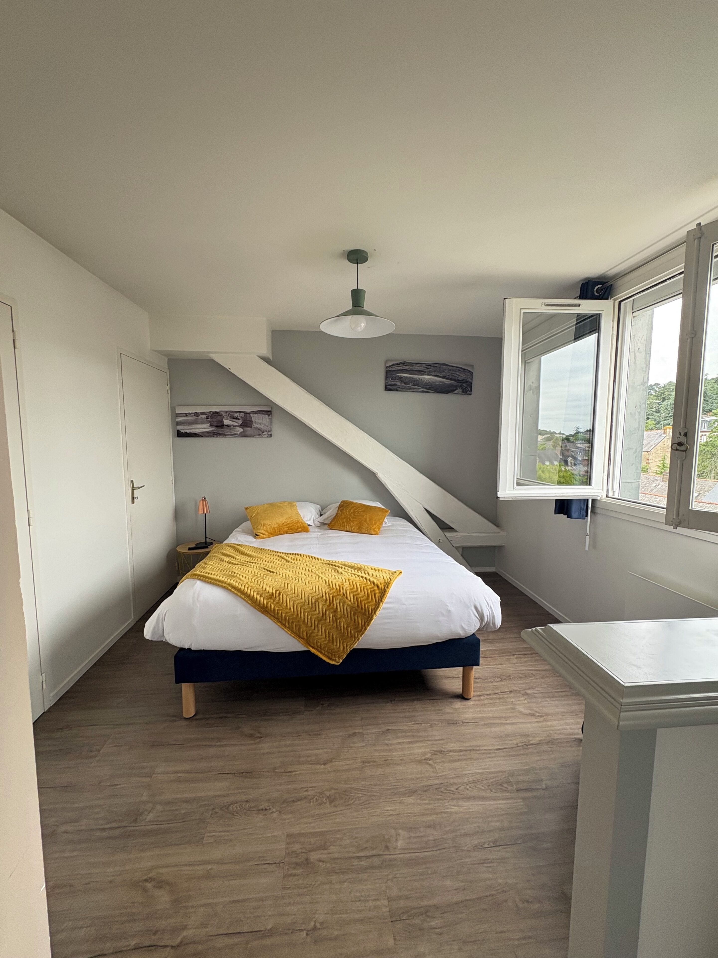 Ein Schlafzimmer mit Bett, Fenster, Lampe und einem Bild an der Wand.