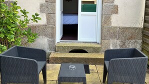 A stone building with a window, a small step leading to a door, and two wicker chairs with a table in front. - Hôtel de Bretagne (Redon)