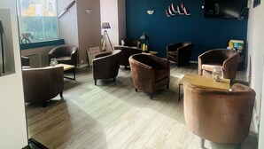 A modern living room with a curved ceiling, a large window, and a blue accent wall. - Hôtel de Bretagne (Redon)