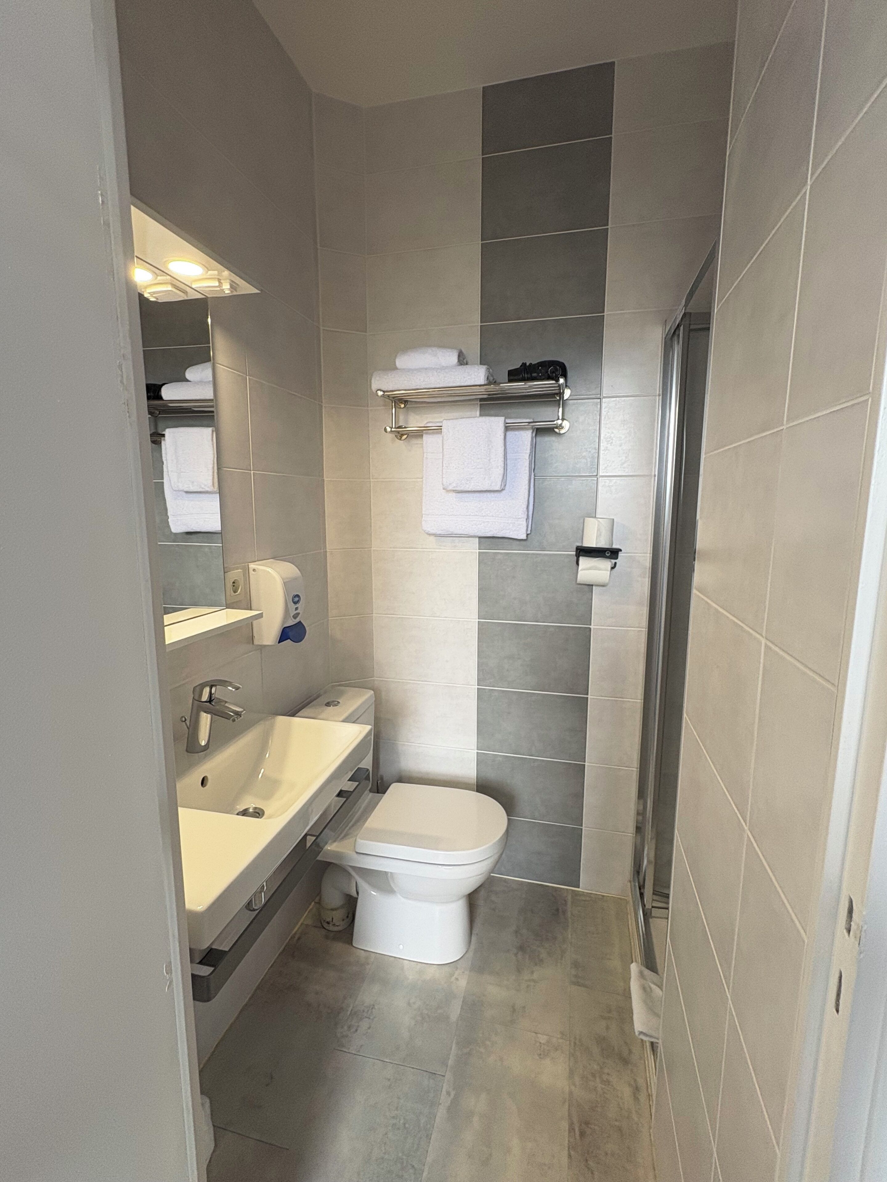A compact bathroom with a toilet, sink, and towel rack.