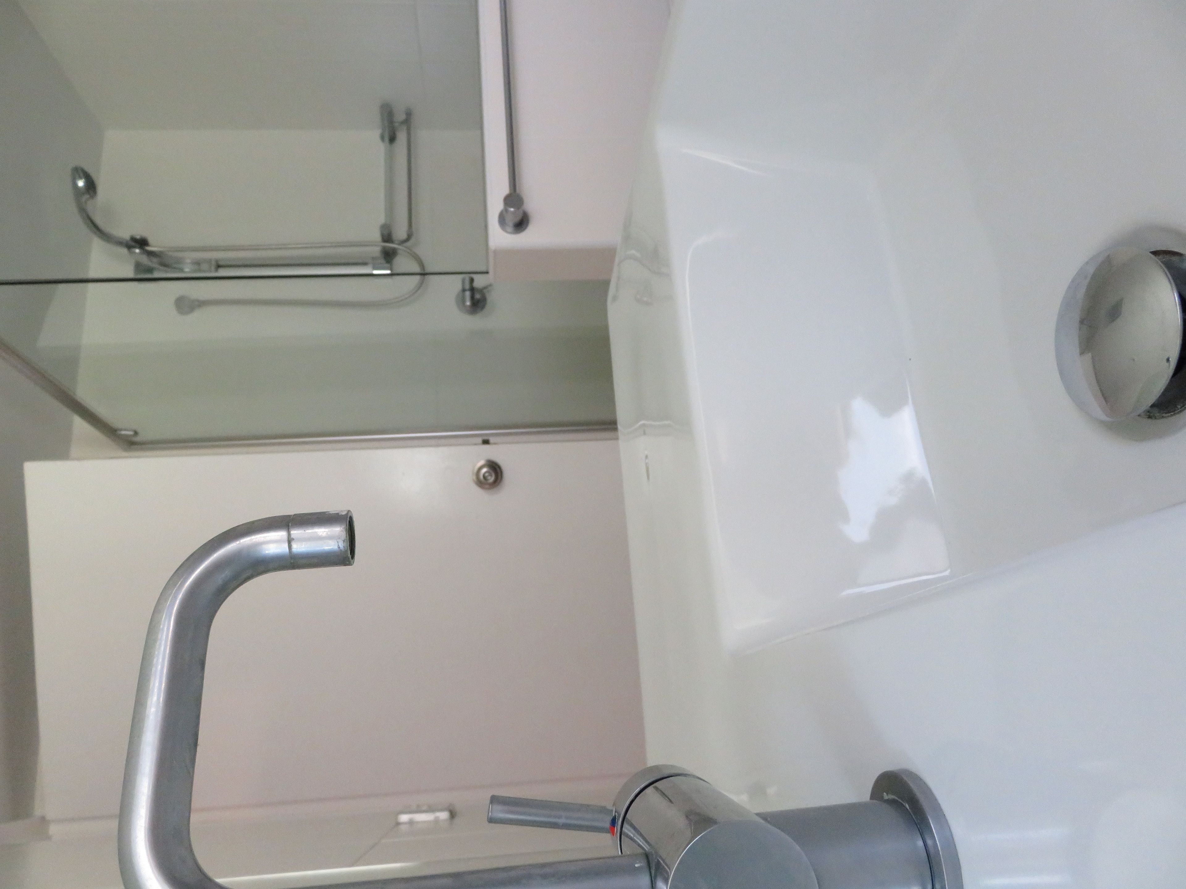 A modern bathroom with a glass shower enclosure, a chrome faucet, and a wall-mounted toilet.