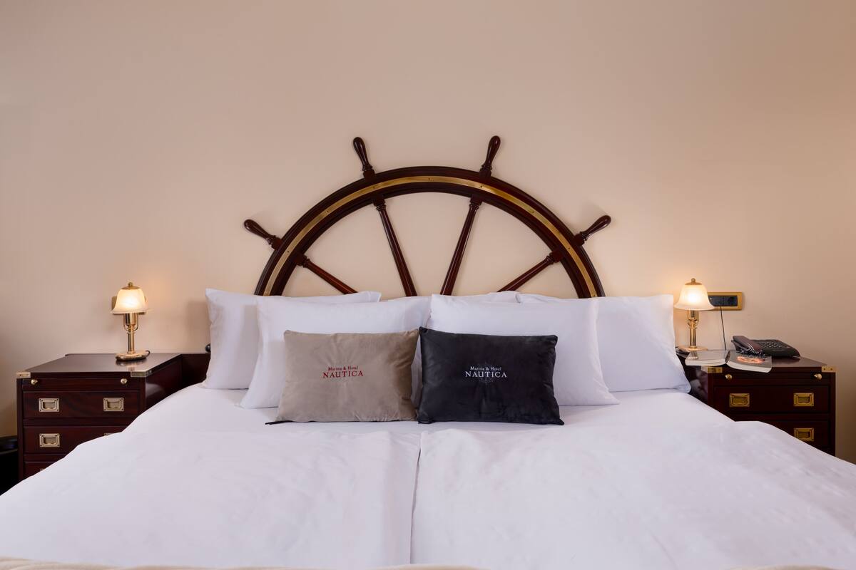 A neatly made bed with a wooden headboard, two bedside tables with lamps, and two pillows with text.