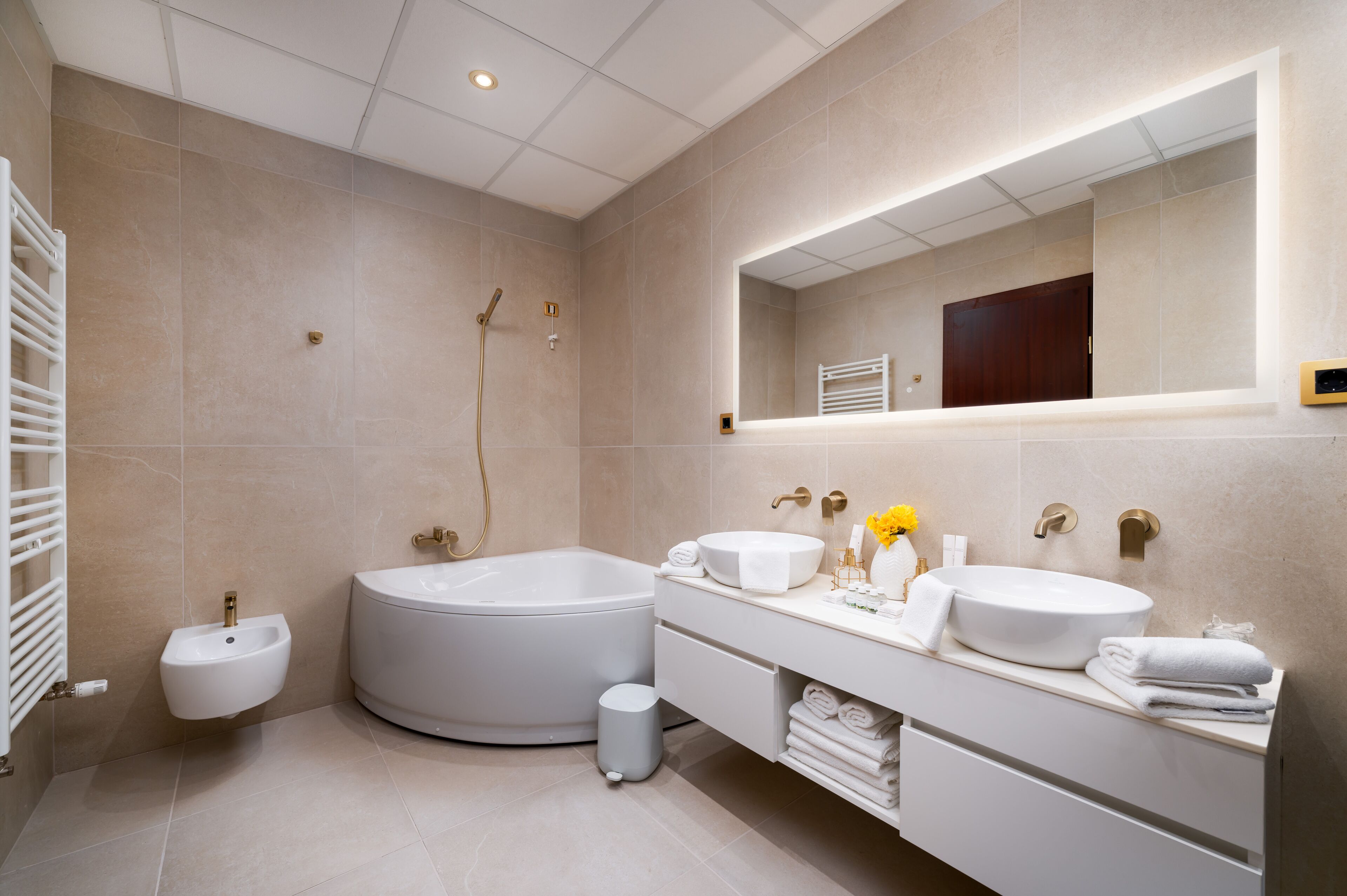 A modern bathroom with a bathtub, two sinks, a vanity, and a large mirror.