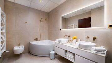 A modern bathroom with a bathtub, two sinks, a vanity, and a large mirror.