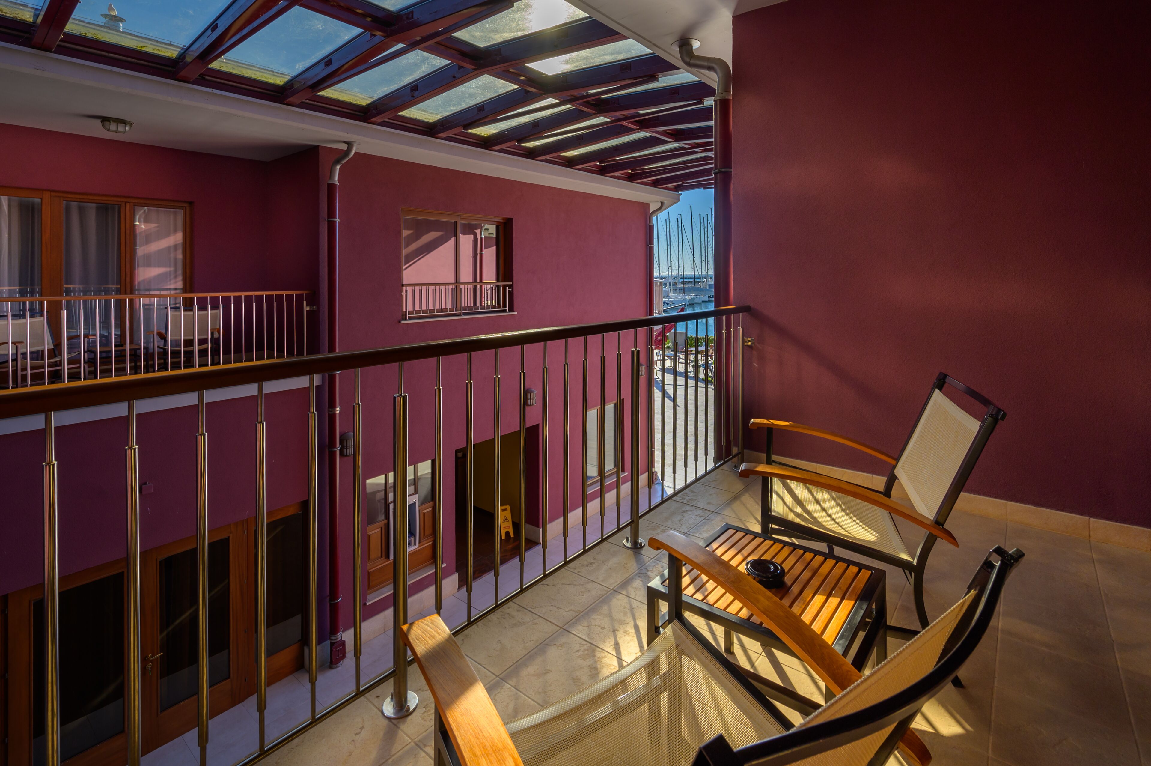 A balcony with a view of the sea, a wooden table, and chairs.