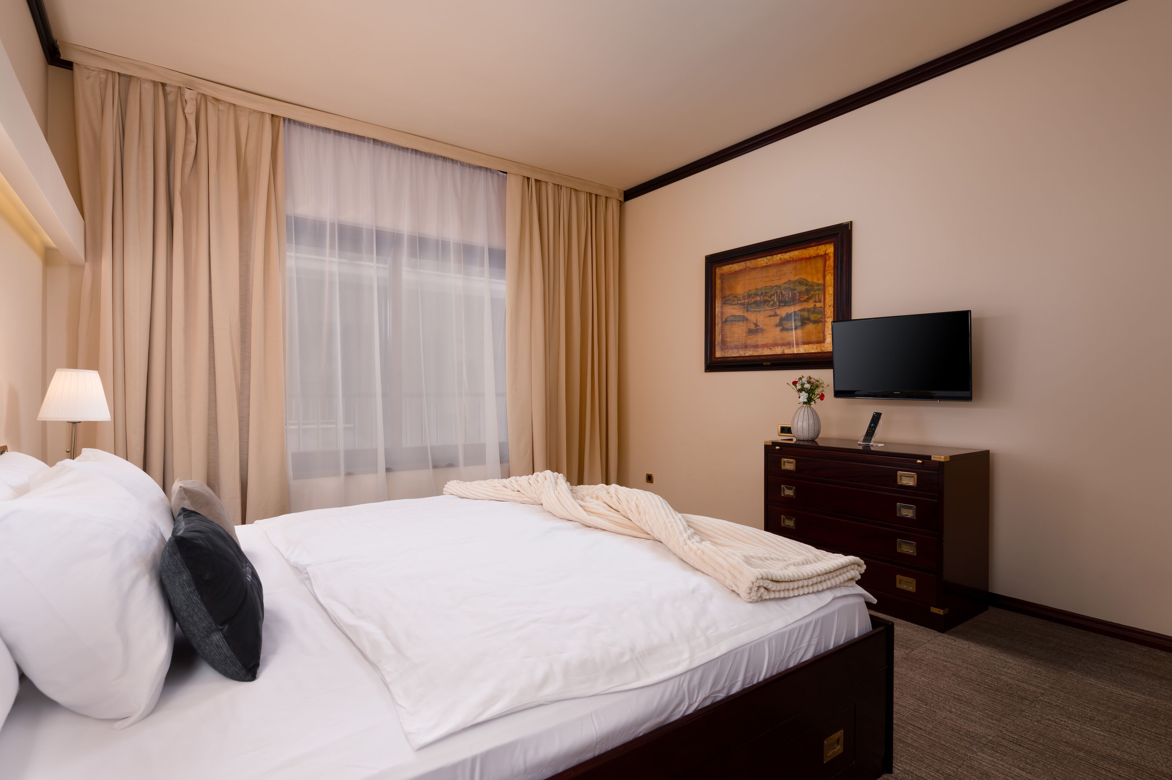 Een hotelkamer met een bed, een televisie, een dressoir en een schilderij aan de muur.