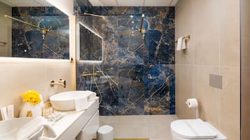A modern bathroom with a white sink, marble backsplash, and a glass-enclosed shower.