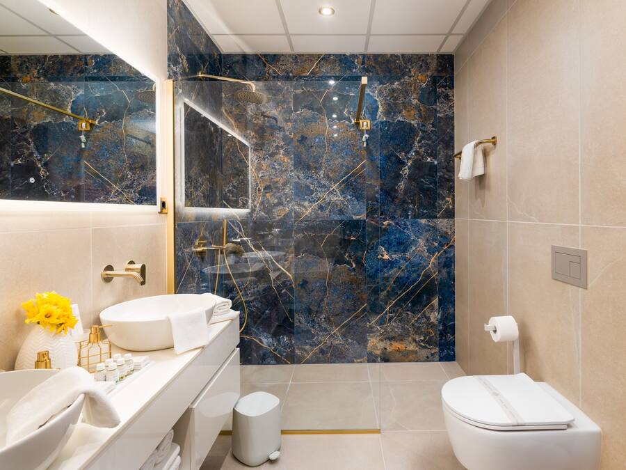 A modern bathroom with a white sink, marble backsplash, and a glass-enclosed shower.