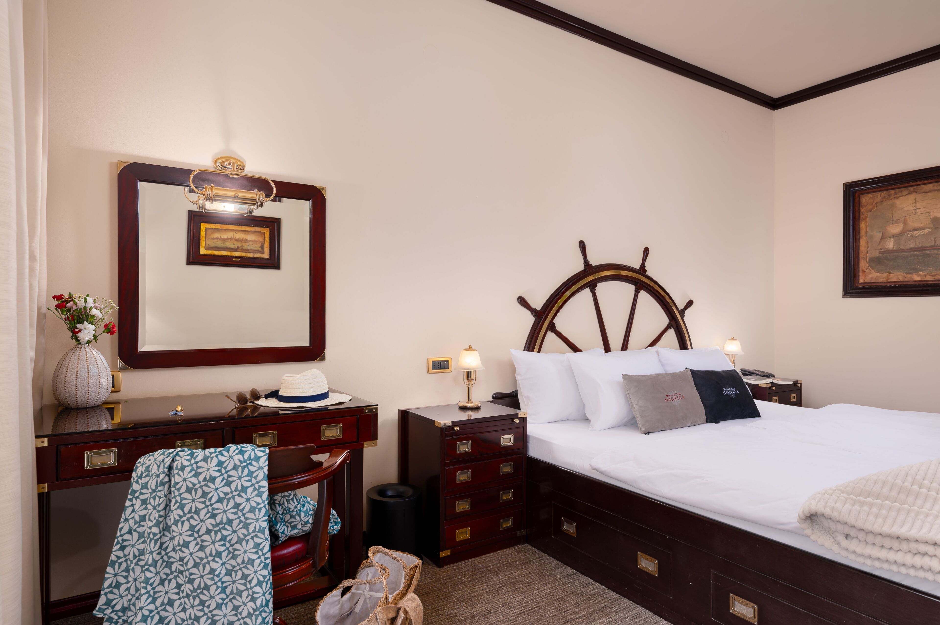 A neatly arranged bedroom with a bed, dresser, vanity, and a mirror.