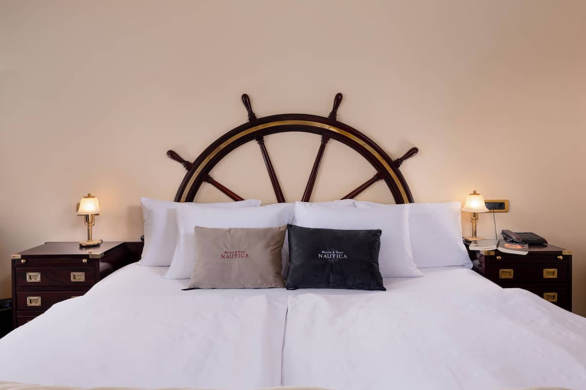 A neatly made bed with a wooden headboard, two bedside tables with lamps, and two pillows with text.