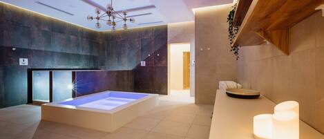 Un moderno espacio de spa con piso calefaccionado, un espejo grande y techo de madera.