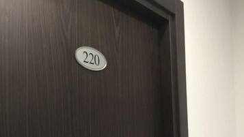 A dark wooden door with a white number plate displaying '220'.