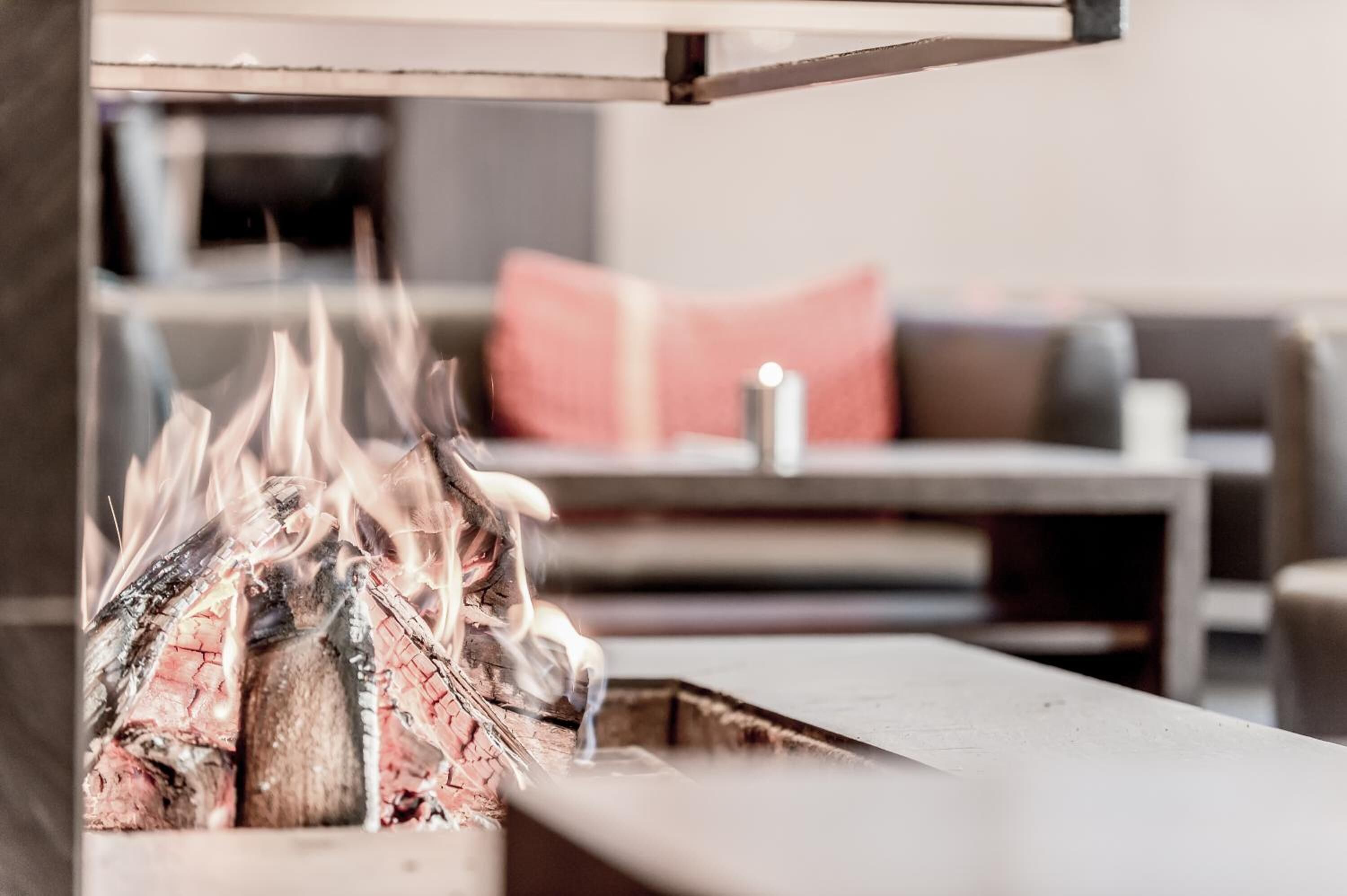 A fireplace with burning logs in a modern living room with a sofa and a coffee table.