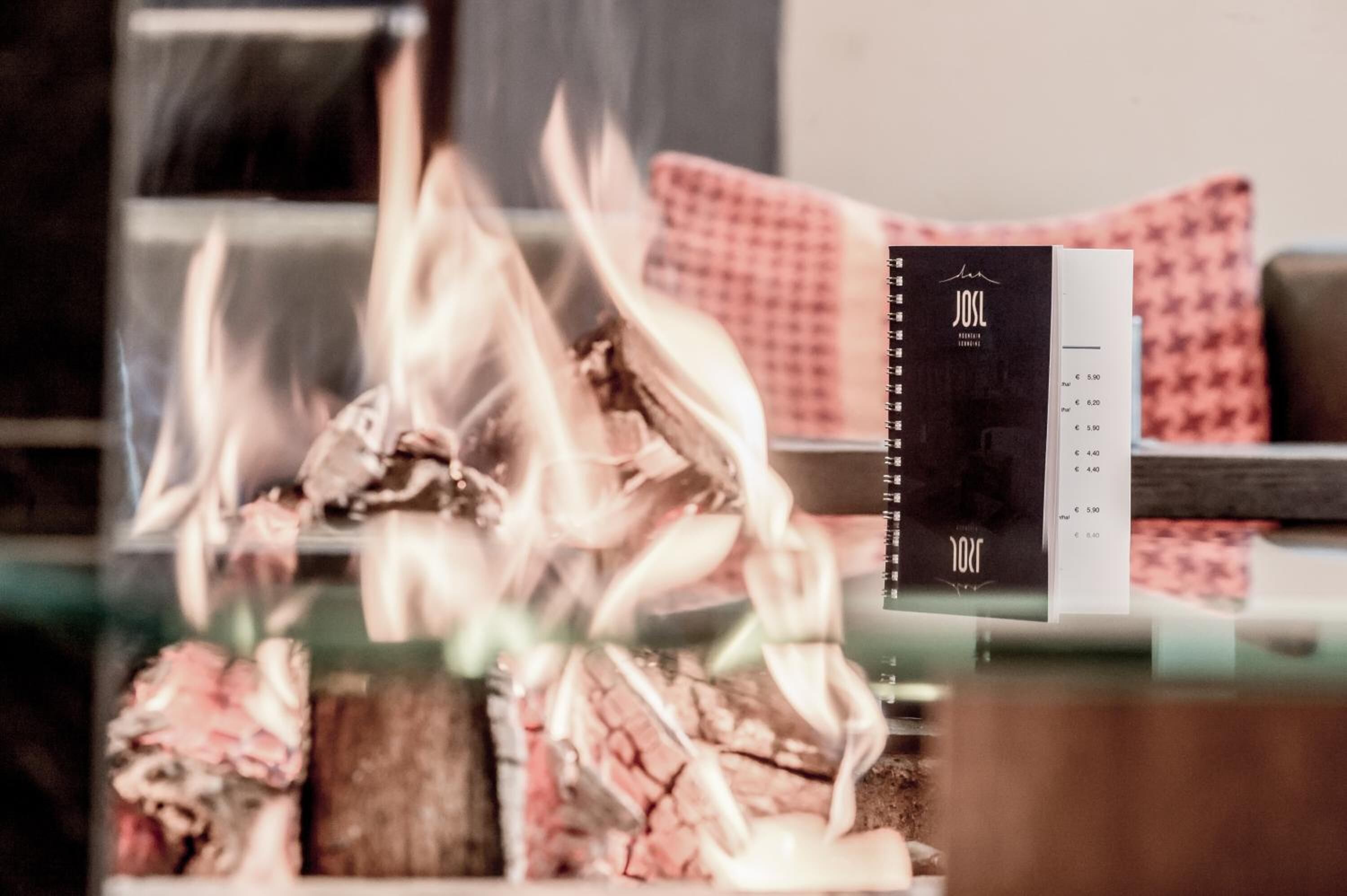 A fire with logs and a menu on a table.