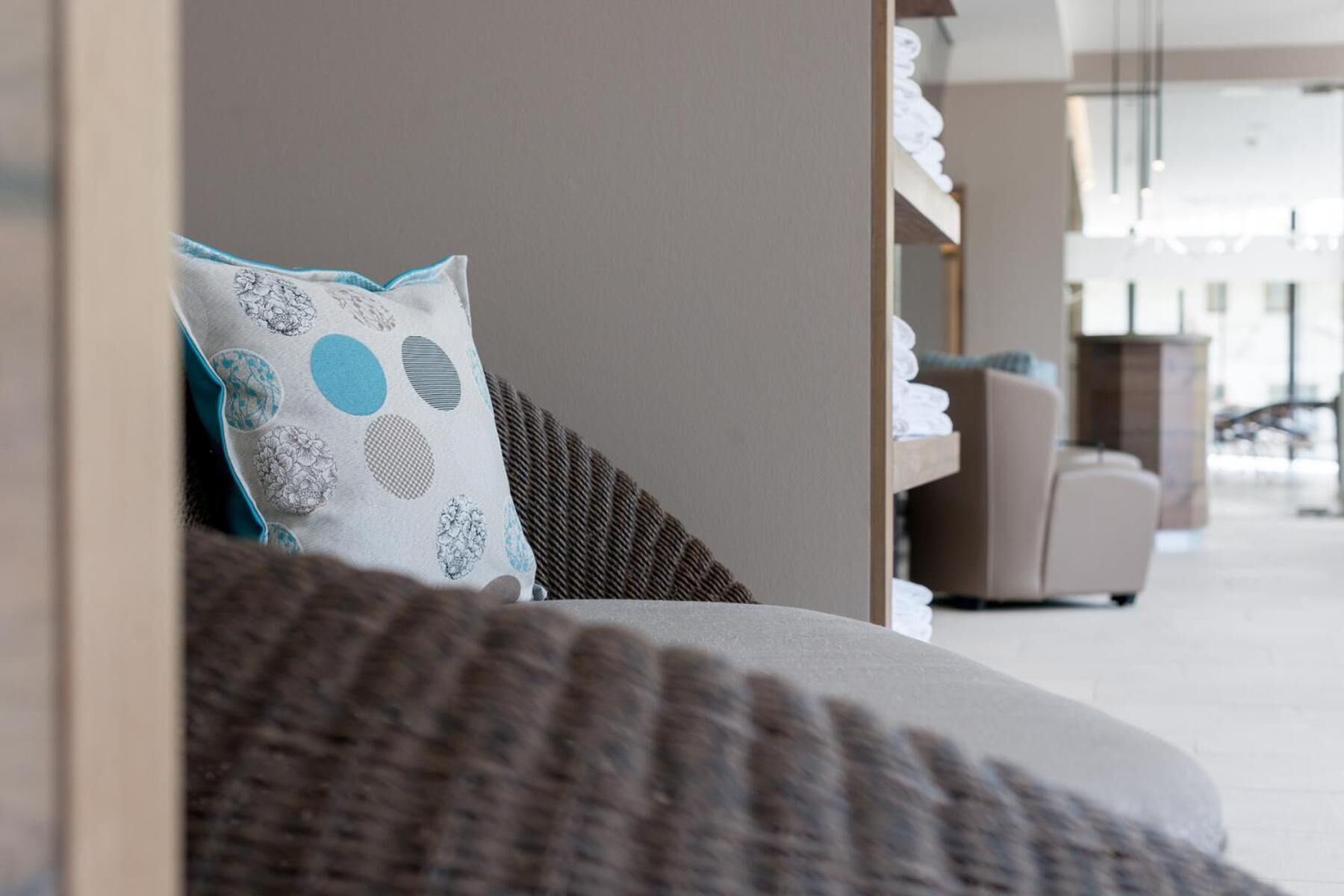 Una sala moderna con un sofá, un cojín estampado y vista a un pasillo con una silla y una encimera.