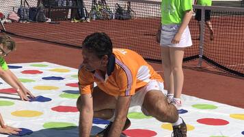 Een tennisbaan met een kleurrijke mat, een net en een hek.