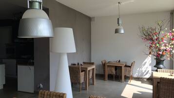 Ein stilvoller Essbereich mit einem zentralen Tisch, umgeben von Korbstühlen, und einer großen weißen Lampe.