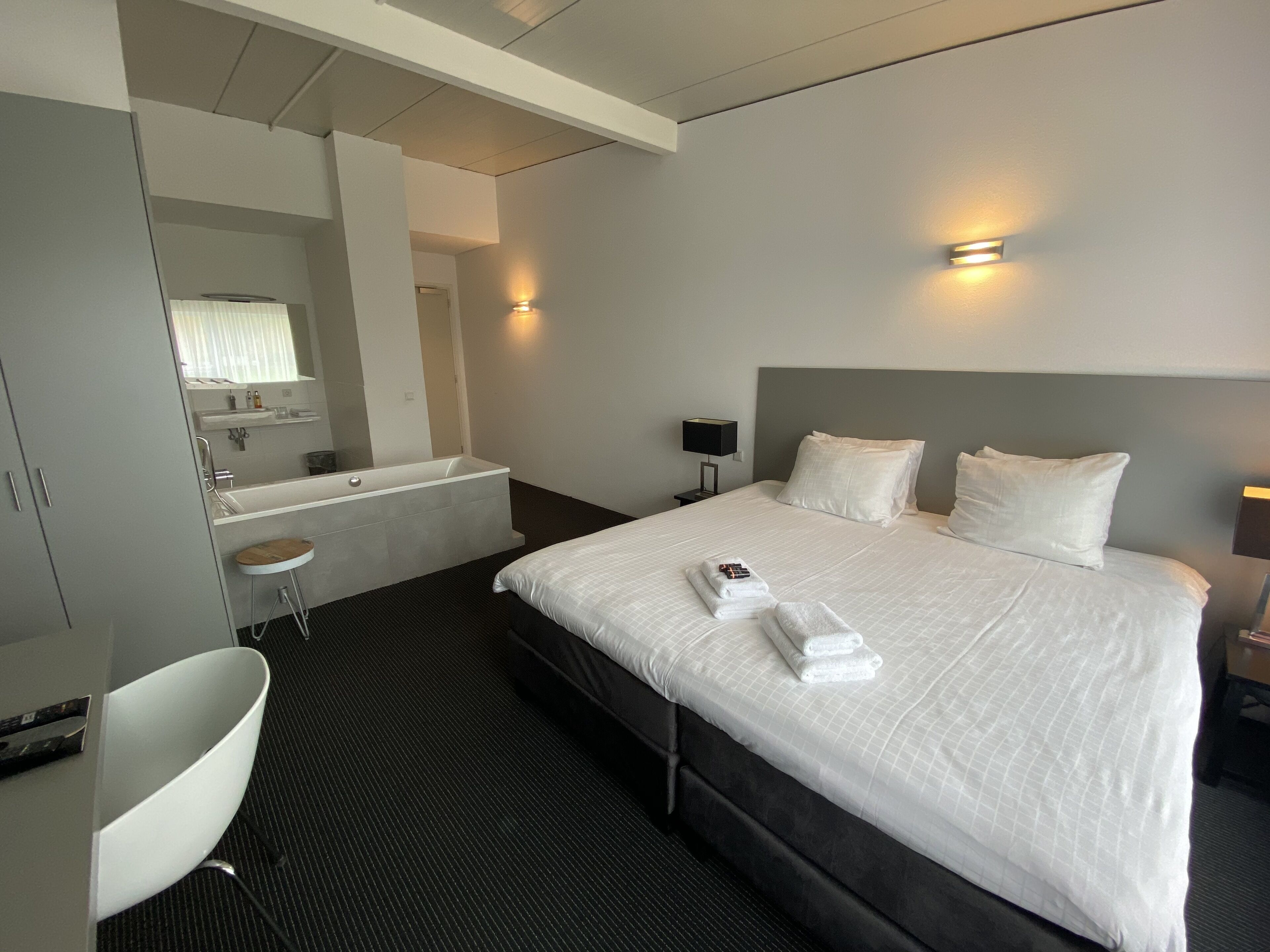 A hotel room with a large bed, a separate bathroom, a desk, and a chair.
