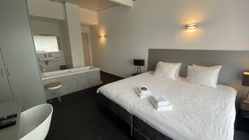 A hotel room with a large bed, a separate bathroom, a desk, and a chair.