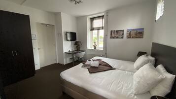 Ein Schlafzimmer mit einem Bett, einem Schreibtisch, einem Fernseher und einem Fenster mit Jalousien.