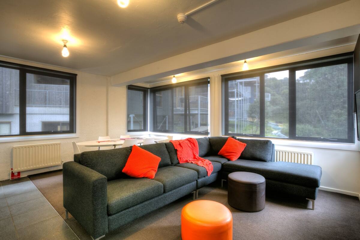 A modern living room with a sectional sofa, ottoman, and a small table.