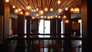 A bar area with multiple hanging pendant lights, a counter, and red stools. - Silverski (Falls Creek)