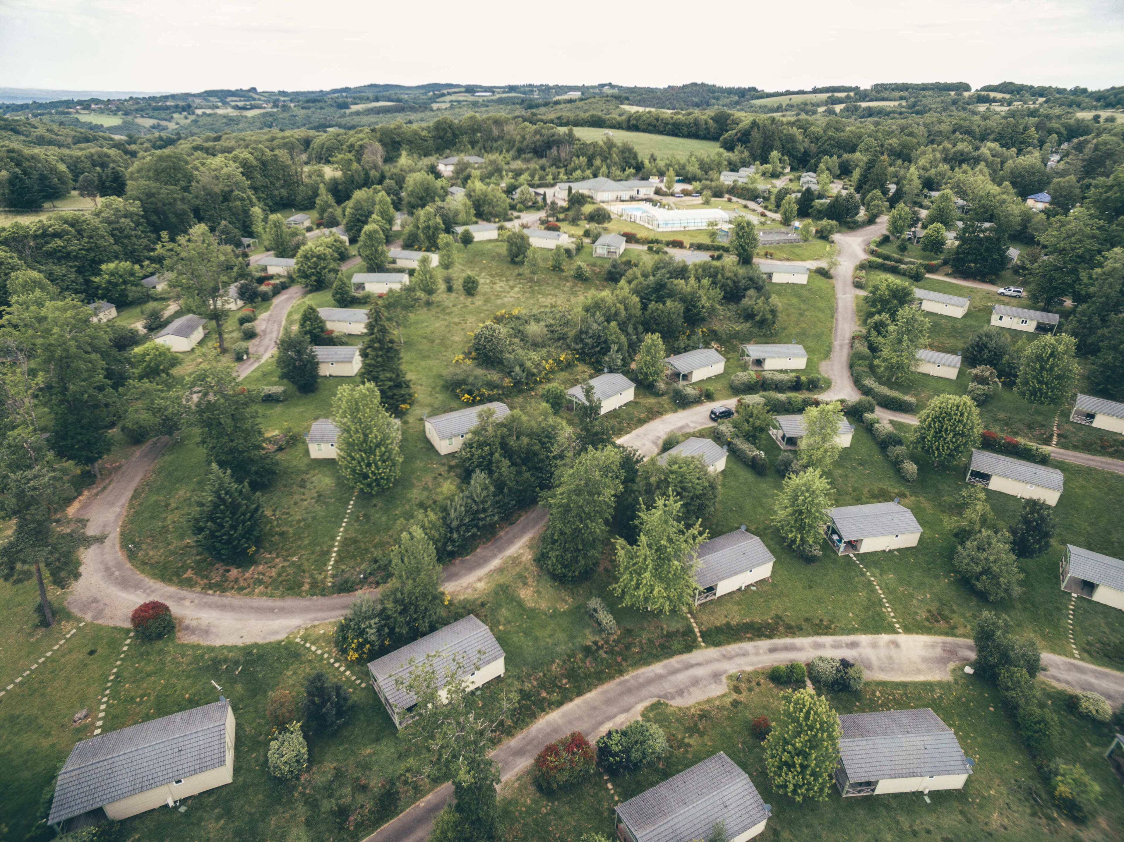 Luchtbeeld van een woongebied met meerdere huizen, wegen en groene ruimtes.