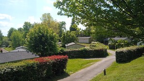A residential area with a paved road, neatly trimmed hedges, and houses with sloped roofs. - Terres de France - Les Hameaux de Miel (Beynat)