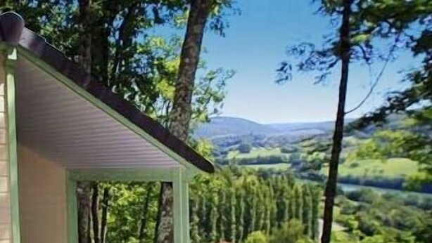 A covered outdoor seating area with a view of a green landscape. - Terres de France - Les Hameaux de Correze (Lissac-sur-Couze)