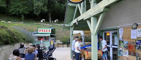 An outdoor seating area with a pizza stand and a beer sign.
