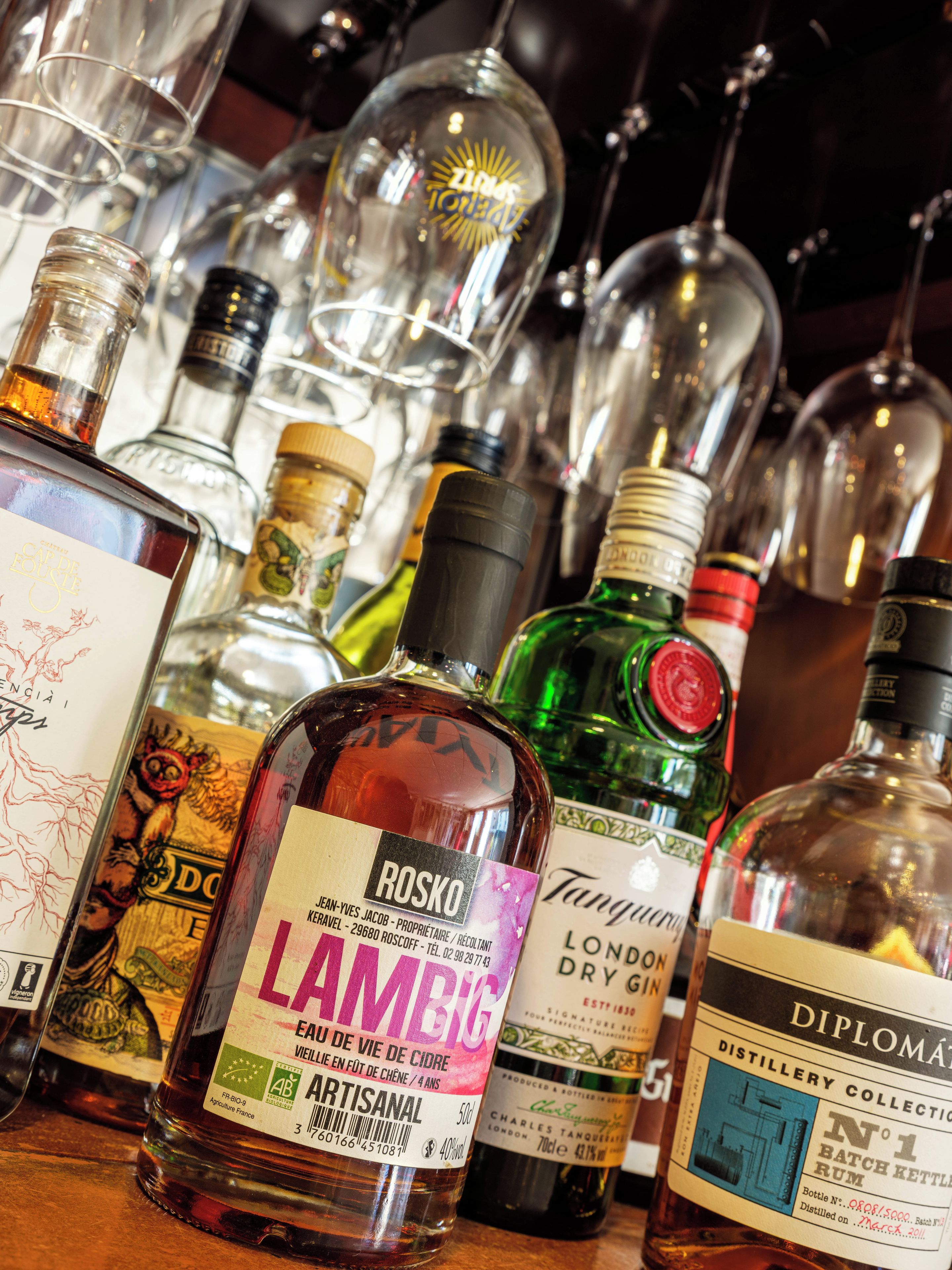 A variety of liquor bottles on display, including brands like Rosko and Lambic.