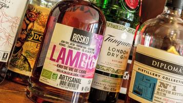 A variety of liquor bottles on display, including brands like Rosko and Lambic.