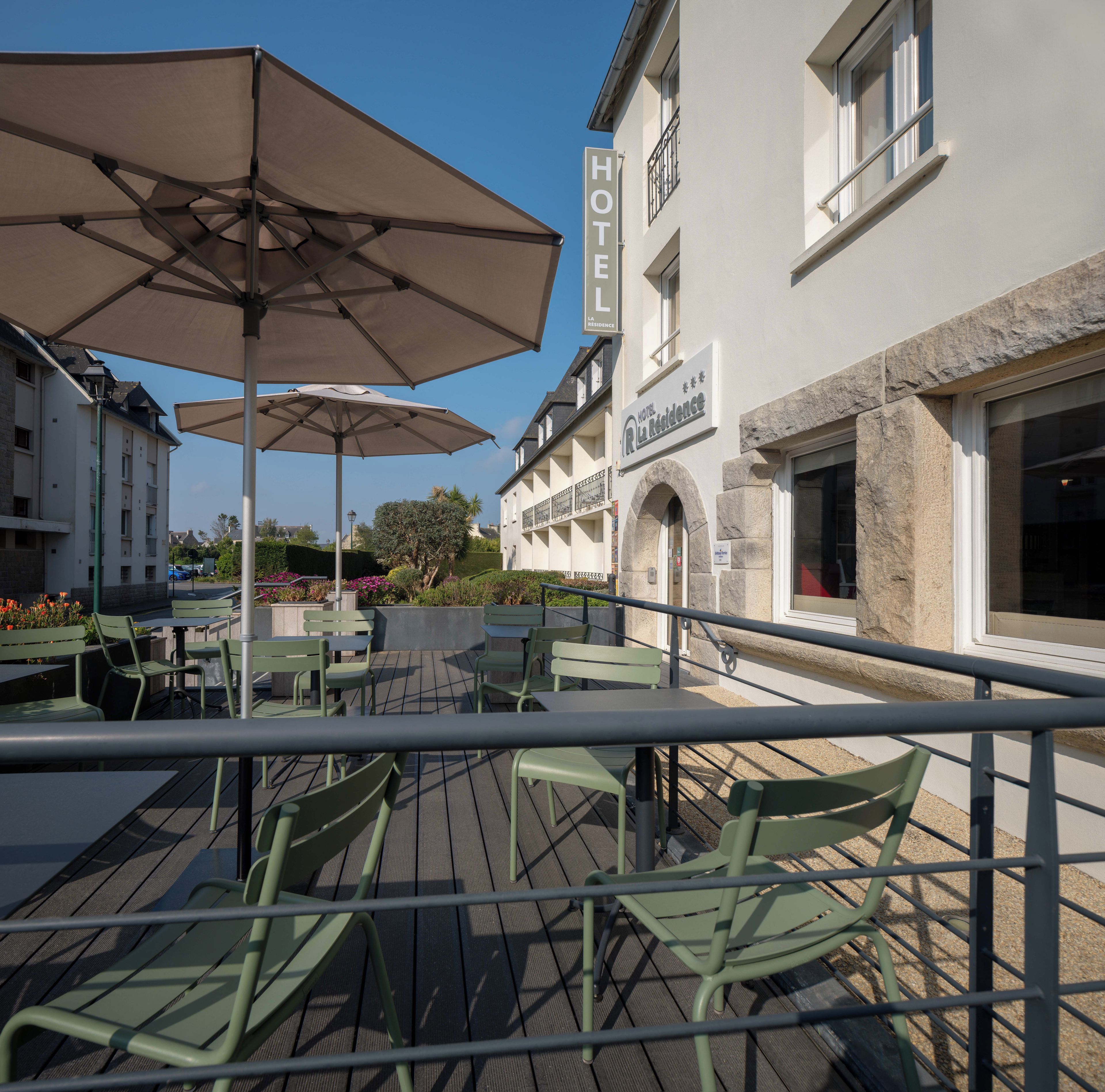 An outdoor seating area with tables and chairs, a hotel sign, and a stone building facade.