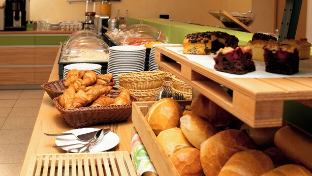 A buffet with various breads, pastries, and a cake. - Hotel Mariaweiler Hof (Dueren)