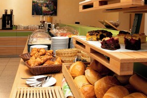 A buffet with various breads, pastries, and a cake. - Hotel Mariaweiler Hof (Dueren)