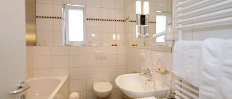 Un baño moderno con bañera, inodoro, lavabo y espejo.