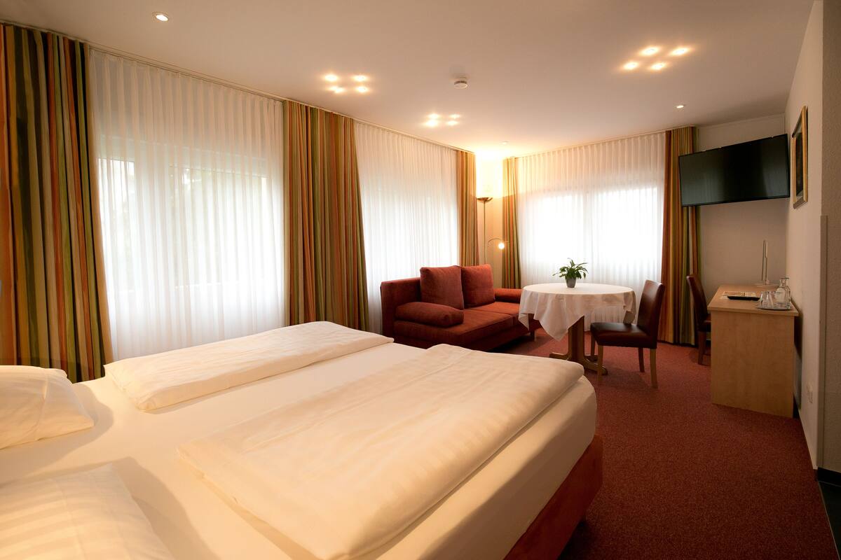 Una habitación de hotel con una cama grande, un sofá, una mesita y un televisor.