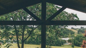 Un espacio al aire libre techado con vistas a un campo verde y árboles.