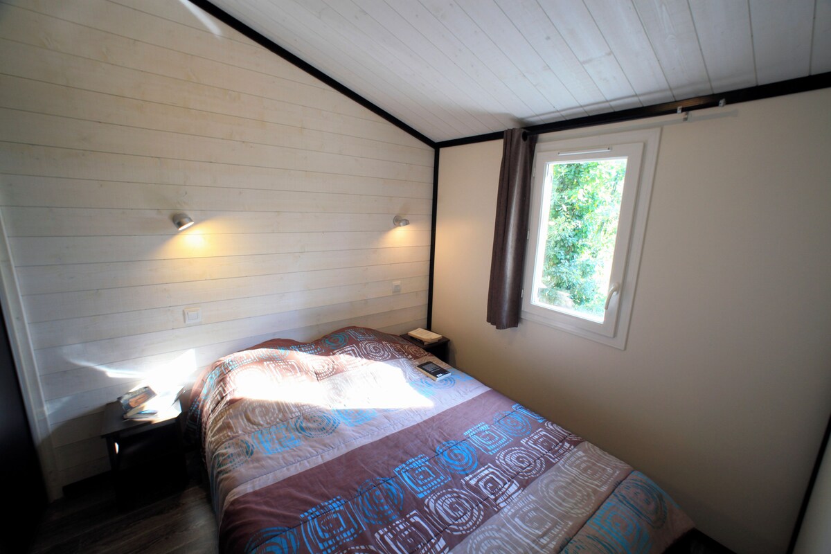 A bedroom with a bed, bedside tables, a window, and a ceiling light.