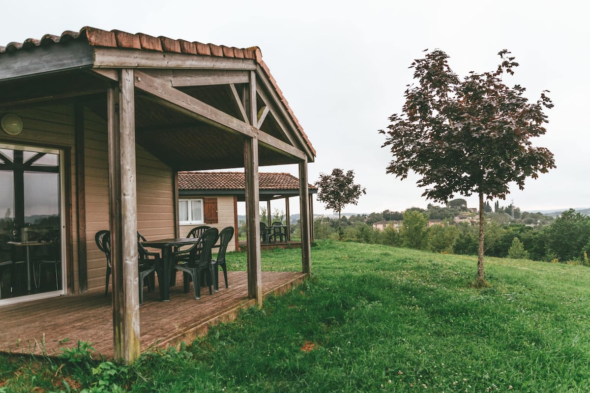 A wooden house with a porch, a table, and chairs.