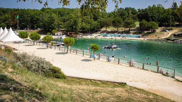Una playa con piscina, tiendas de campaña y un bote.