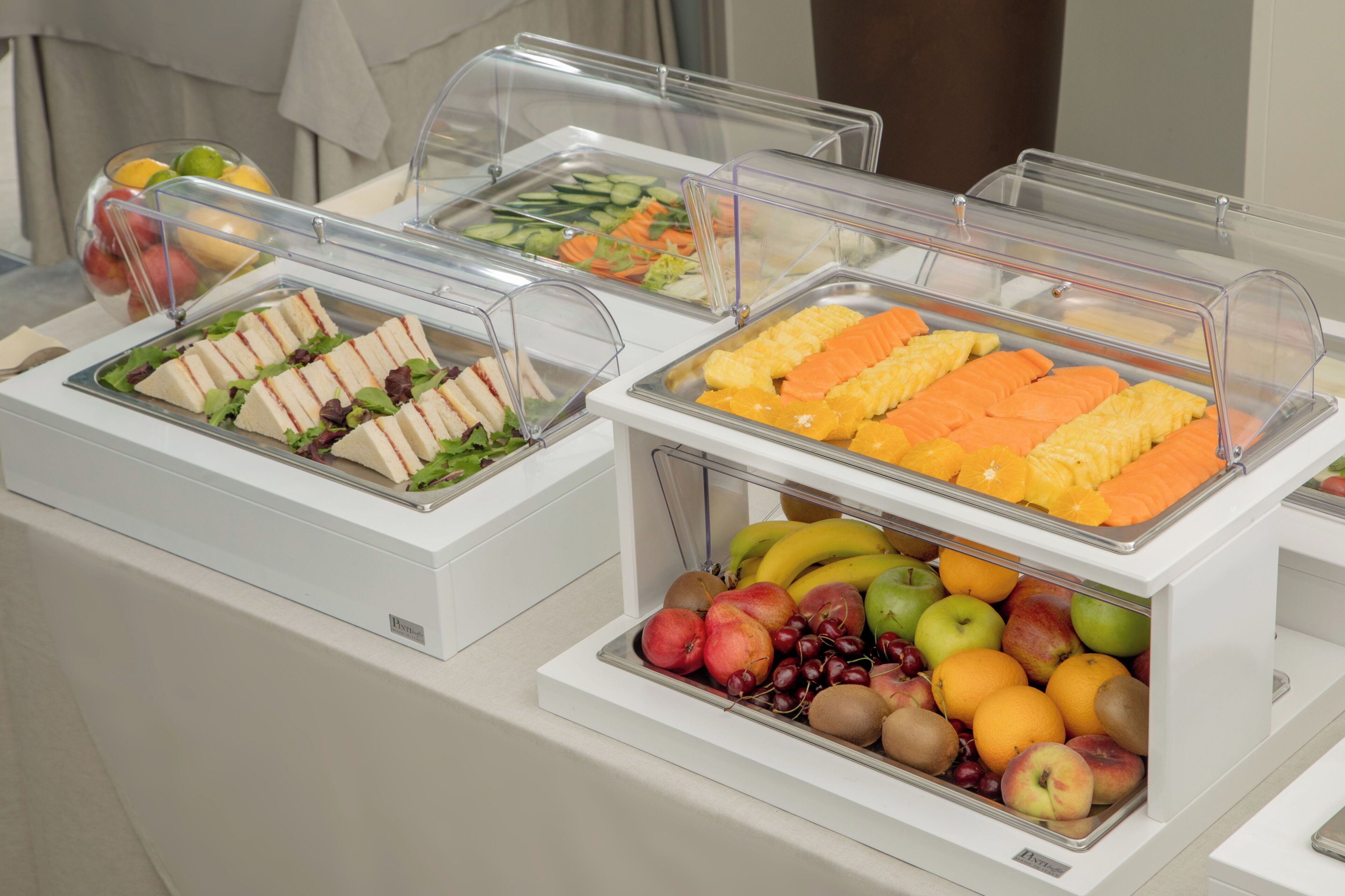 A buffet with various food options including sandwiches, fruits, and vegetables.