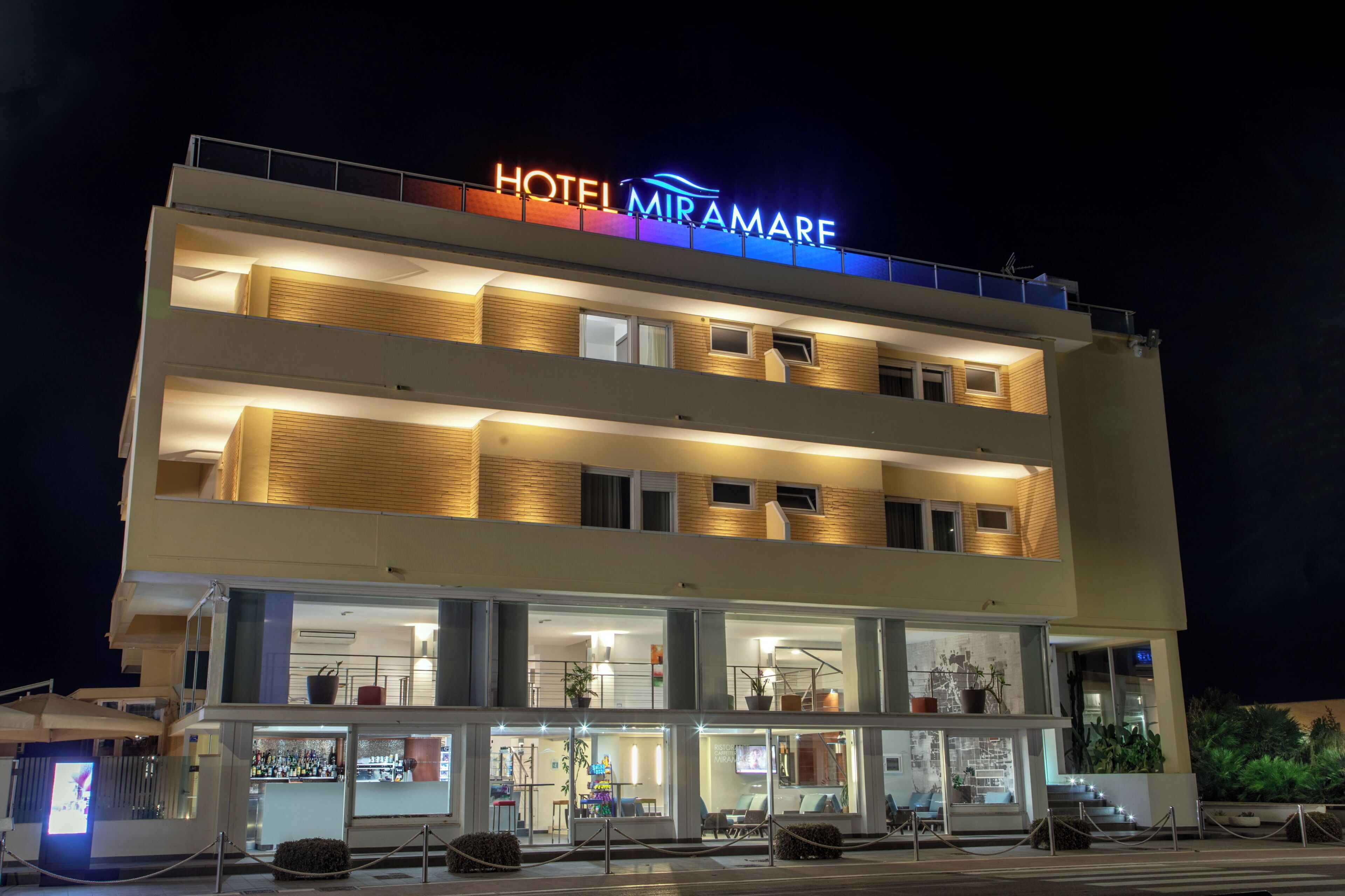 A multi-story hotel with a prominent illuminated sign reading 'HOTEL MIRAMARE.'