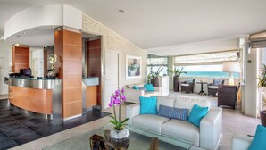 A modern hotel lobby with a reception desk, seating area, and a view of the ocean. - Hotel Miramare (Latina)
