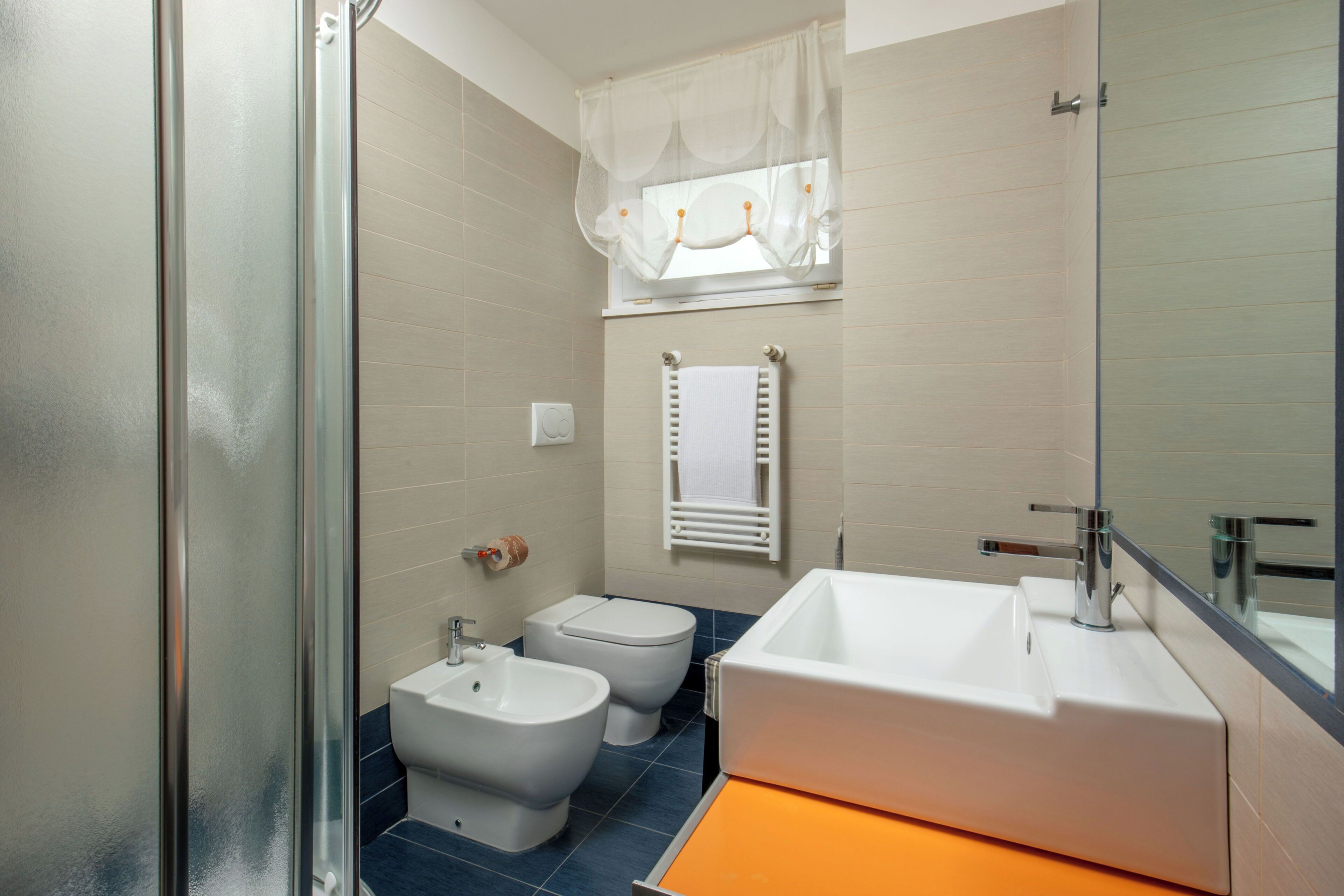 Ein Badezimmer mit Dusche, Bidet, Toilette und einem großen Waschbecken.